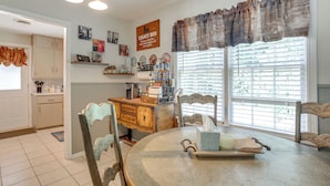 A kitchen with a dining table, chairs, a coffee maker, and a window with blinds. - Legacy Run: Guthries Historic Haven Near Shops (Guthrie)