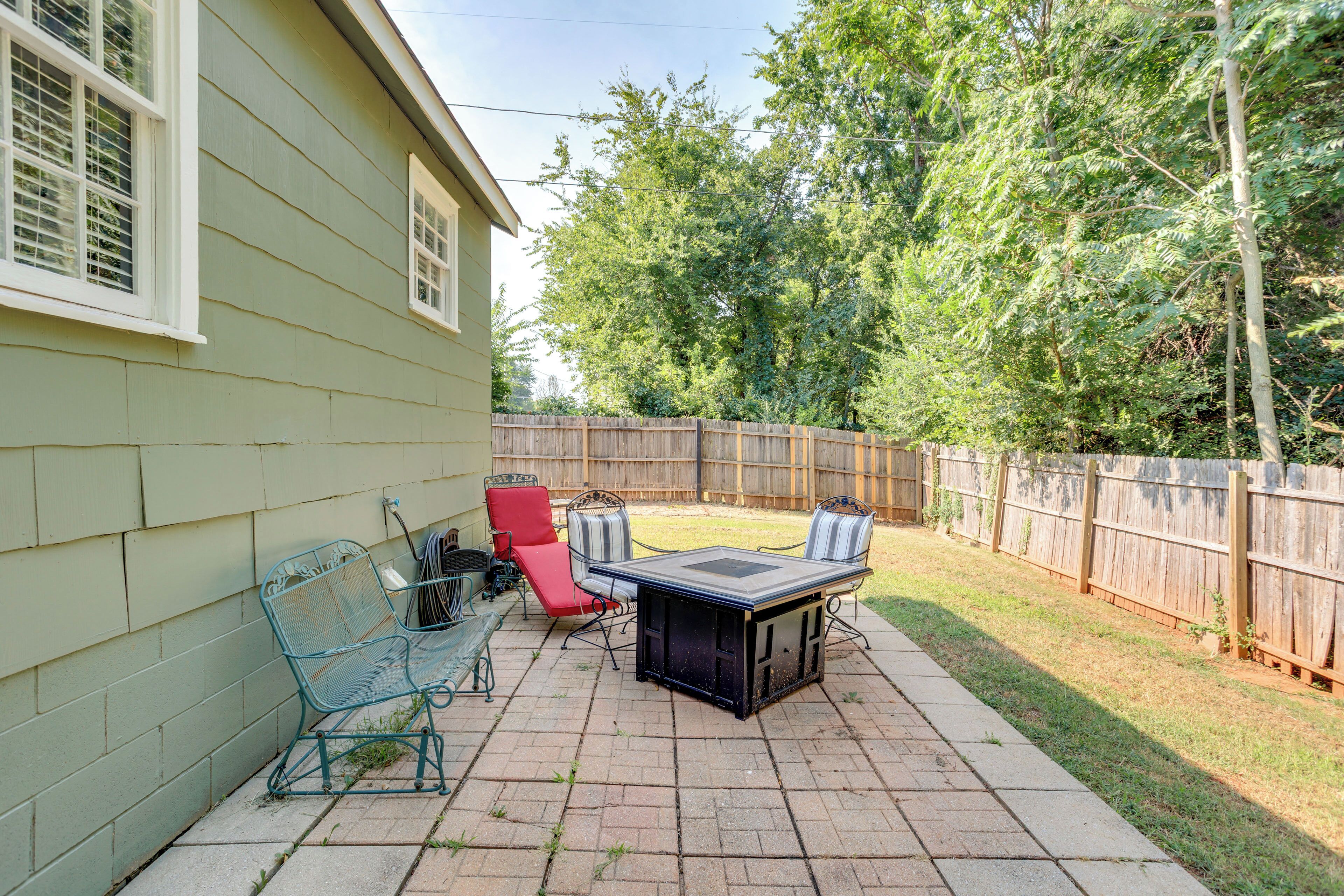 A patio with a table and chairs, a red chair, and a metal bench.