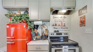 A kitchen with a red Galanz refrigerator, a white stove, and a wall sign that reads "Seasoned with Love." - Legacy Run: Guthries Historic Haven Near Shops (Guthrie)