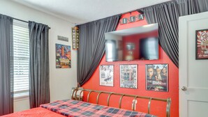 A bedroom with a bed, a TV mounted on the wall, and movie posters. - Legacy Run: Guthries Historic Haven Near Shops (Guthrie)