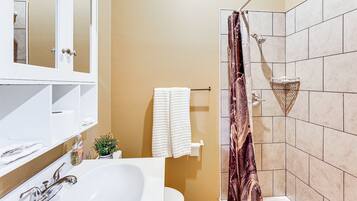 A bathroom with a white sink, a mirror, a toilet, and a shower with a curtain.