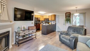 A modern living room with a fireplace, a sofa, a coffee table, and a TV mounted on the wall. - Hike, Fish & Golf: Condo 5 Mi to Ozone Falls! (Crab Orchard)