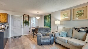 A living room with a gray recliner, a gray sofa, and a dining area with a table and chairs. - Hike, Fish & Golf: Condo 5 Mi to Ozone Falls! (Crab Orchard)
