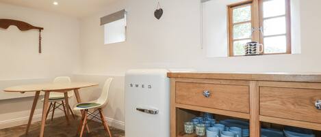 A compact kitchen with a white refrigerator, wooden cabinets, and a dining table with chairs.