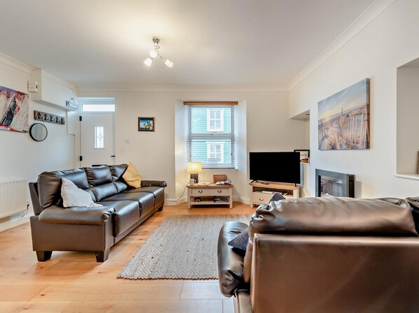 A modern living room with a leather sofa, a TV, and a fireplace.
