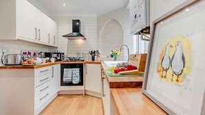 Een moderne keuken met witte kasten, een zwarte afzuigkap en een houten aanrecht.