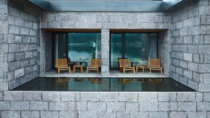 Una habitación moderna con dos ventanas amplias, una piscina de cristal y muebles de madera.
