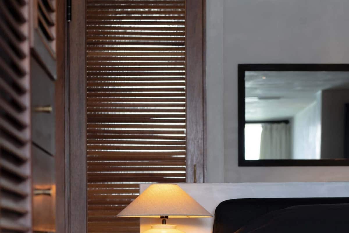 Una habitación de hotel con una cama, una lámpara y un panel divisor de madera.