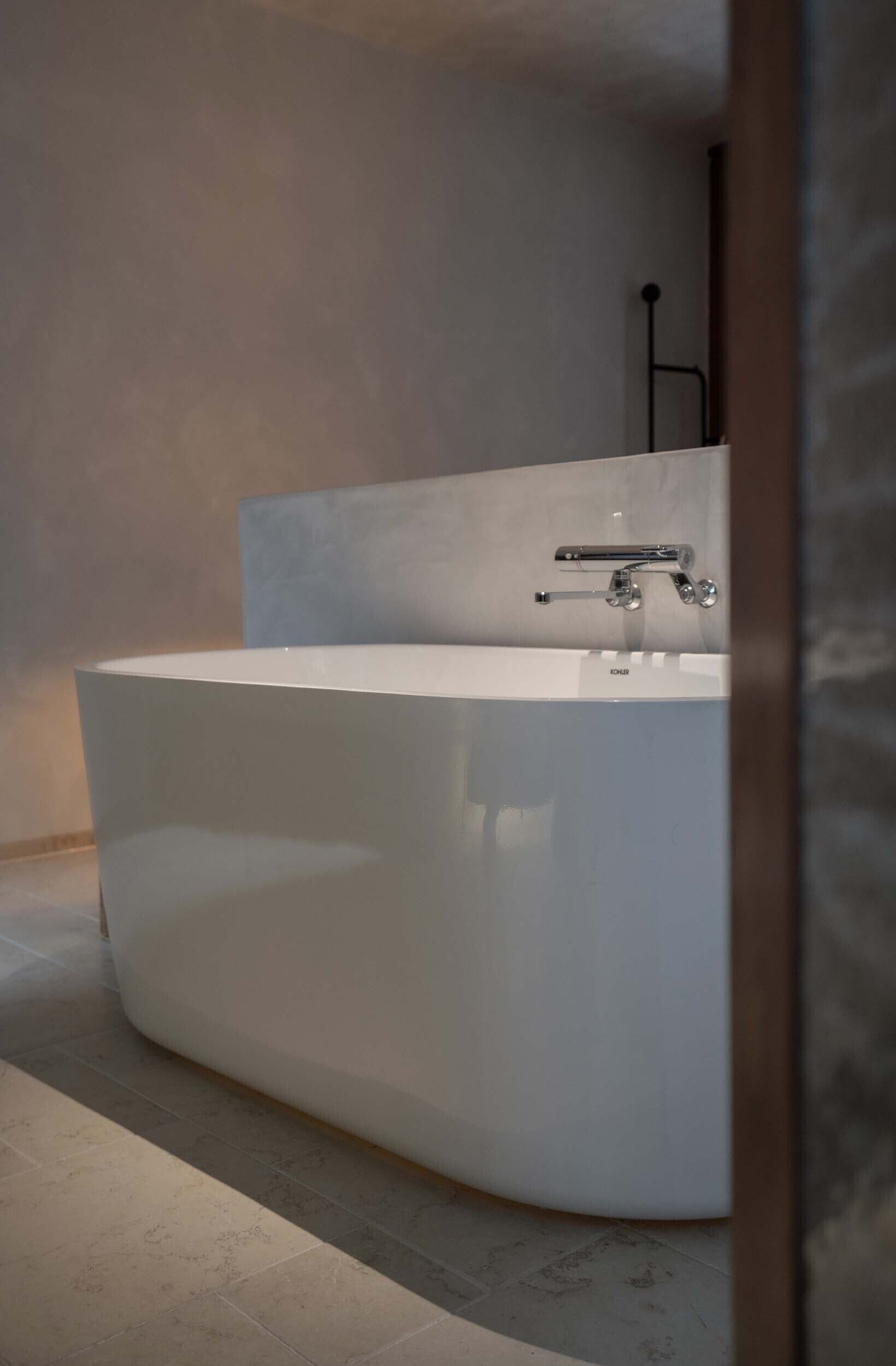 A modern bathroom with a large freestanding bathtub, a minimalist design, and a visible toilet paper holder.