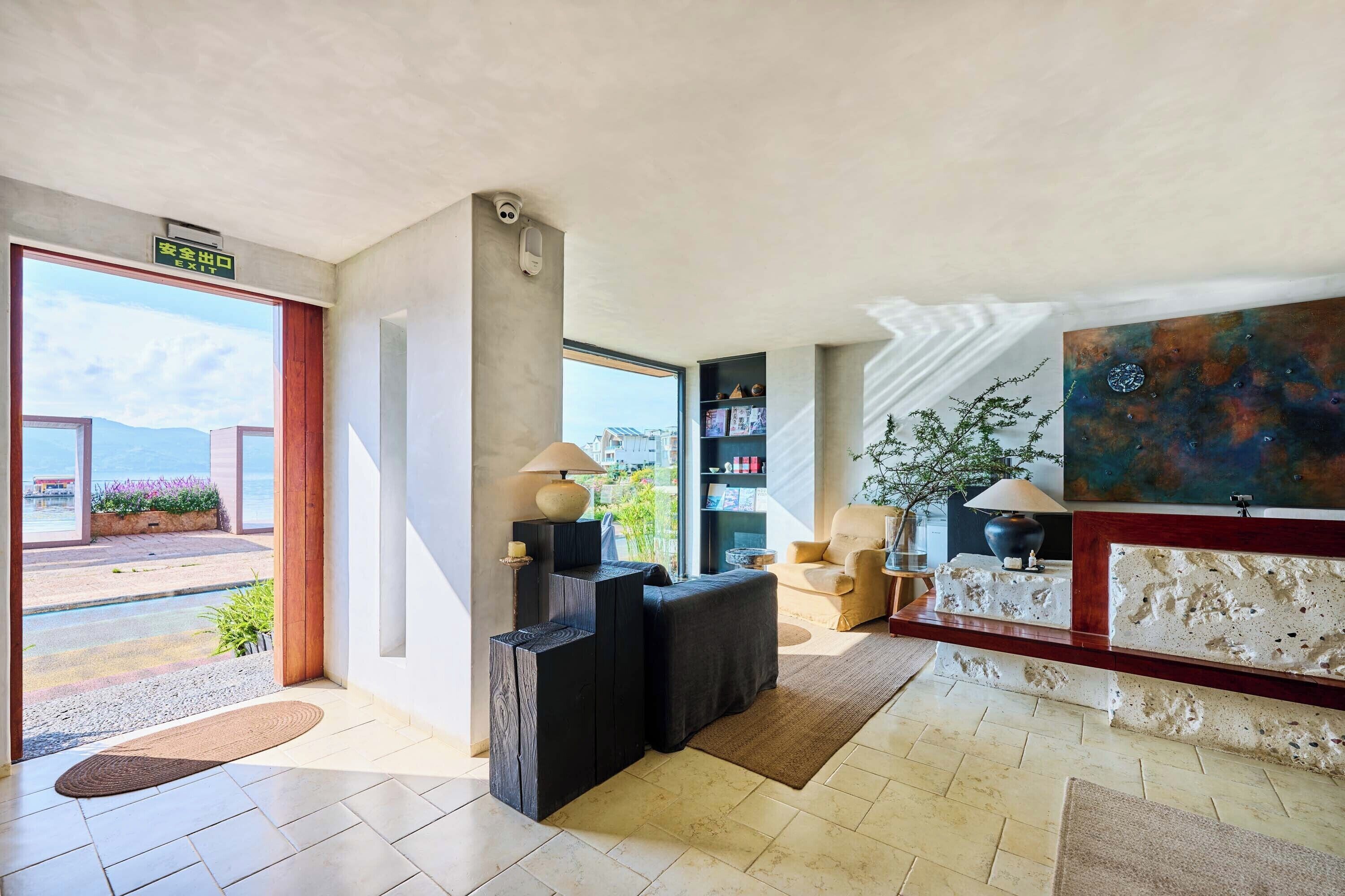 A modern lobby with a reception desk, seating area, and a large window offering a view of the outdoors.