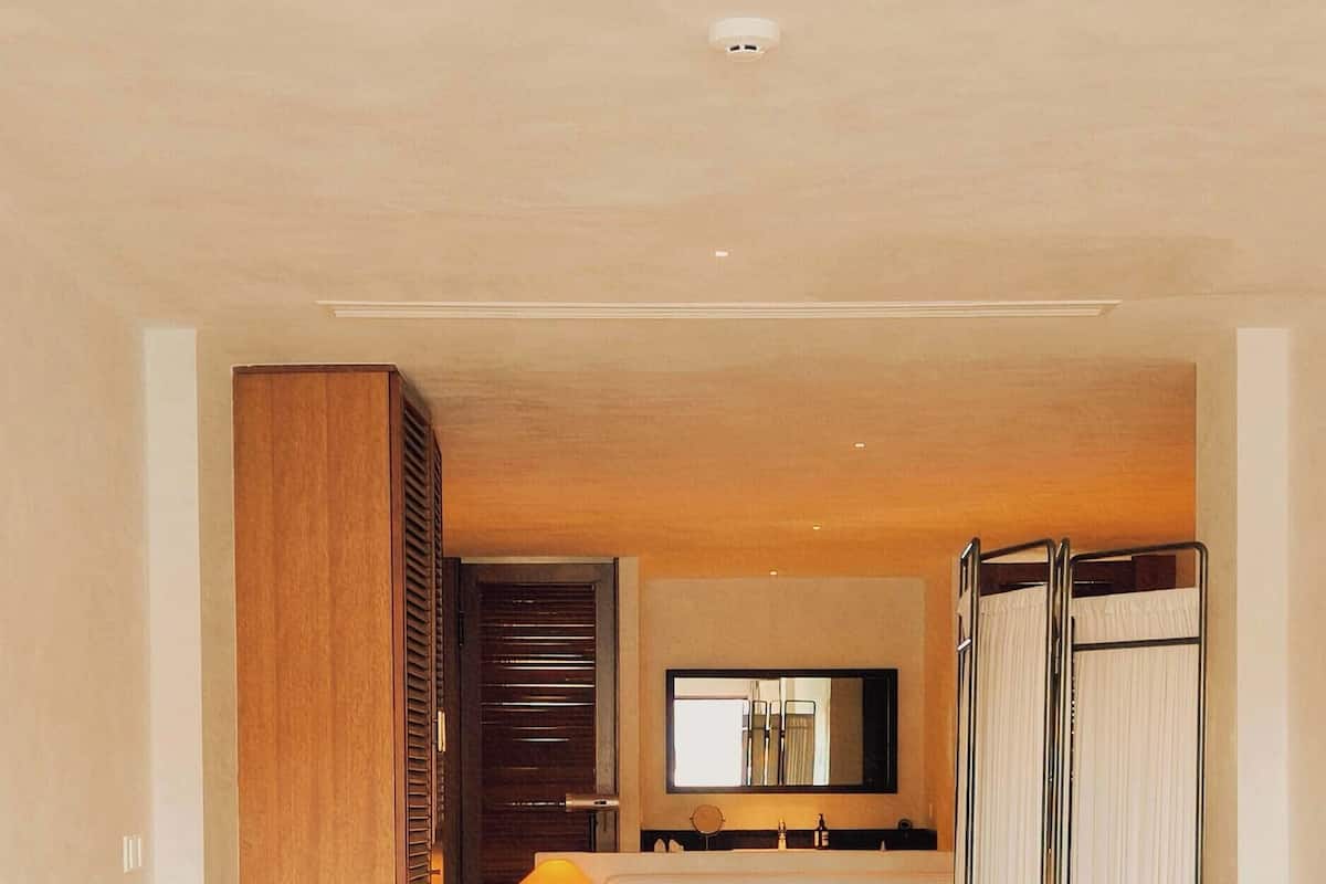 Habitación de hotel con una cama grande, una cama más pequeña, zona de estar con una mesa, televisor y armario.