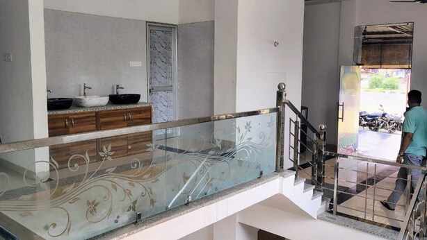 A modern interior with a glass staircase, a marble backsplash, and a view of the outside. - Royal Galaxy Hotel (Shri Madhopur)