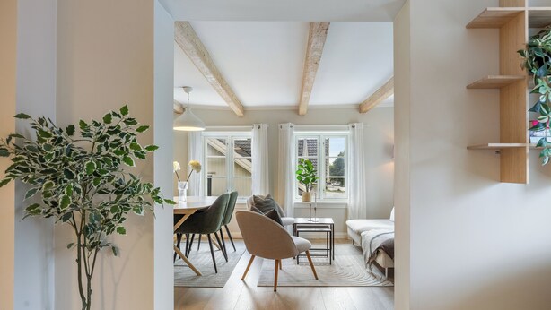 A modern interior with a dining area, a sofa, and a staircase leading to an upper level.