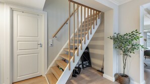 A staircase with wooden steps and a handrail, a white door, and a potted plant.