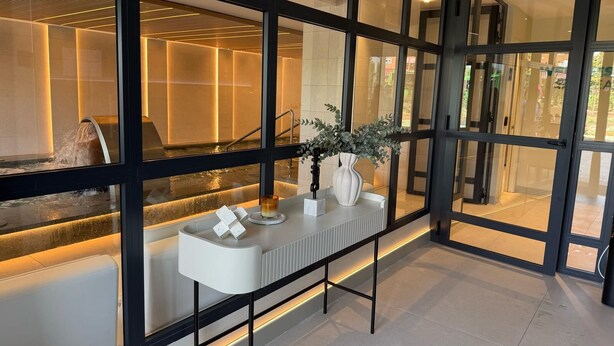 Un interno moderno con un divisorio in vetro, una reception bianca e un elemento decorativo a tema acqua.