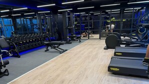 Una palestra con tapis roulant, macchinari per l'allenamento e pesi liberi.