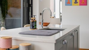 Una cocina moderna con un lavamanos de acero inoxidable, una encimera de madera y una ventana con vistas al exterior.