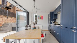 Una cocina moderna con una mesa de madera, armarios azules y un ventanal grande.