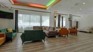 Un salón amplio con televisor de pantalla plana, varios sofás y piso de madera.