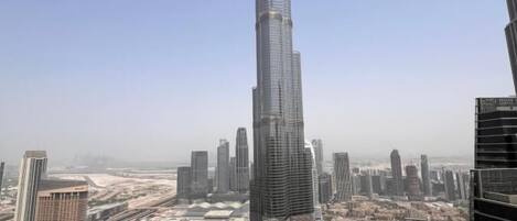 A high-rise building with a distinctive spire, surrounded by other modern skyscrapers and a complex urban layout.