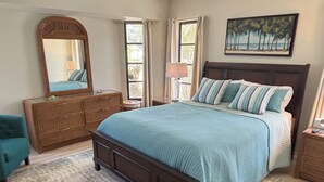 Une chambre à coucher avec un grand lit, une commode, un miroir et un tableau.