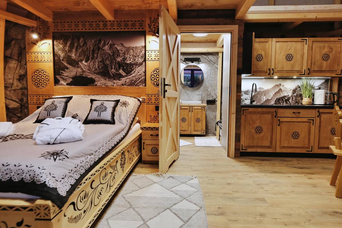 Ein gemütliches Zimmer mit einem Bett, einem Holzschrank und einem Badezimmer mit Waschbecken und Spiegel.