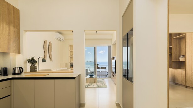 A modern kitchen with a view of the sea, a dining area with a view, and a wooden cabinet. - Ivory by halu (Thessaloniki)