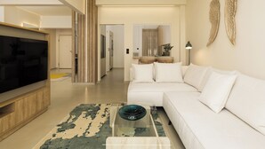 A modern living room with a large flat-screen TV, a white sofa, and a glass coffee table. - Ivory by halu (Thessaloniki)