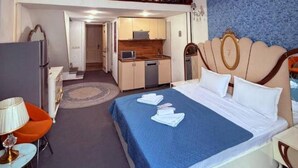 Habitación de hotel con cama, escritorio, kitchenette y balcón.