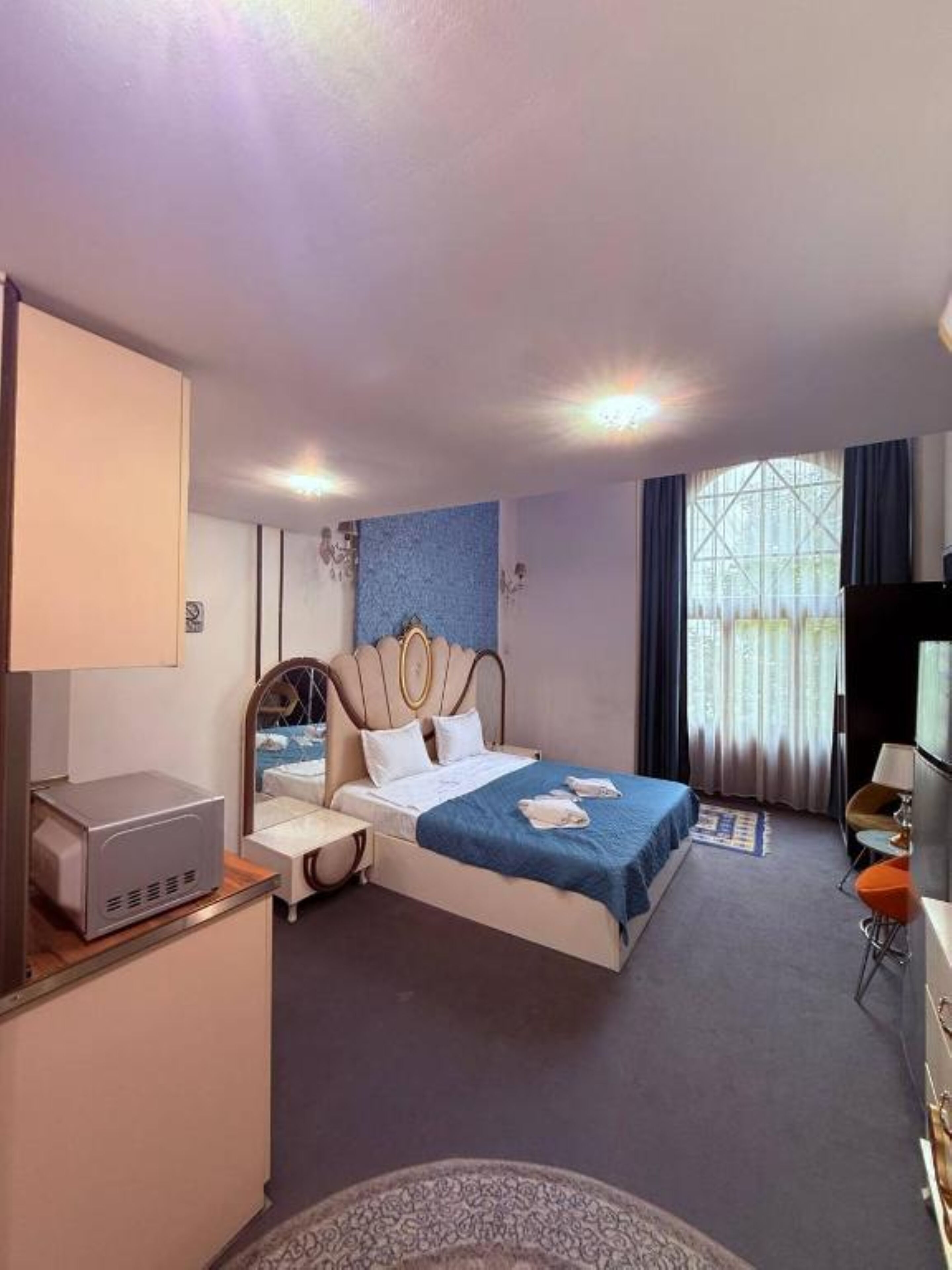 A hotel room with a bed, a desk, a television, and a window with curtains.