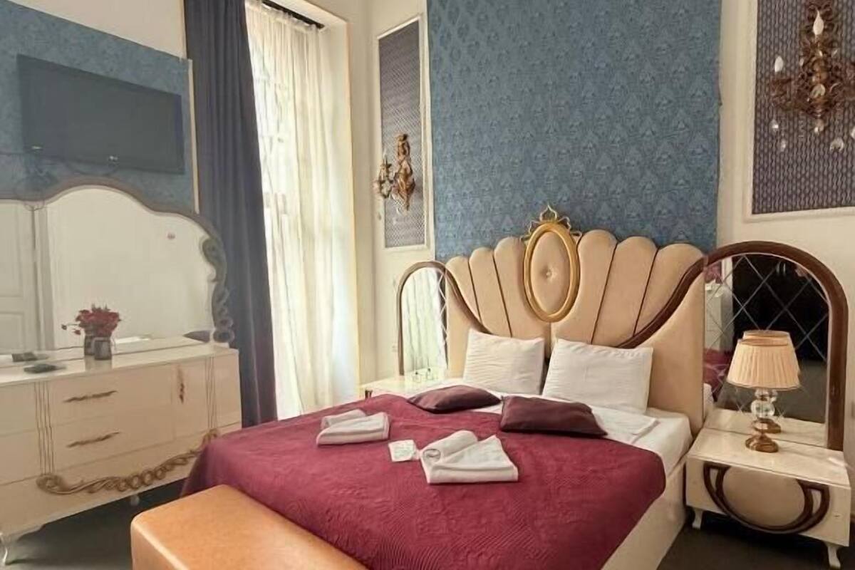 A bedroom with a large bed, a bedside table, a nightstand, a dresser, and a mirror.