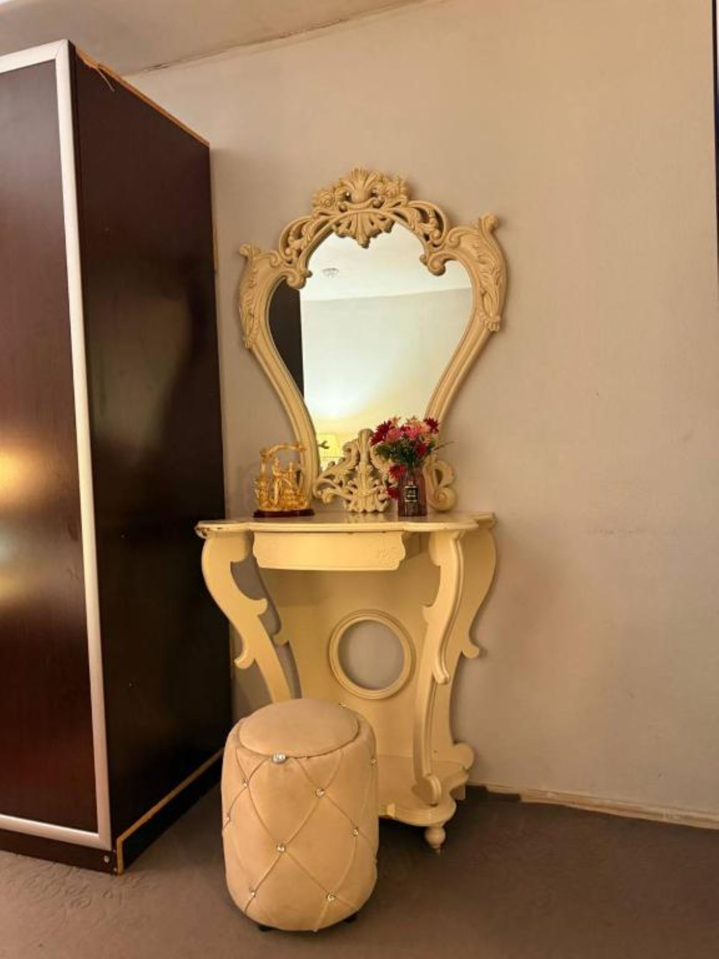 A vanity area with a mirror, a small table, and a stool.