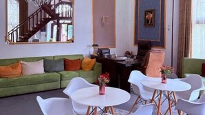 Una sala de estar moderna con un sofá verde, sillas blancas, una araña y una escalera.