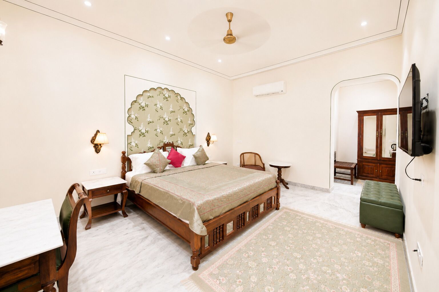 A bedroom with a bed, bedside tables, a desk, a chair, a television, and a wardrobe.
