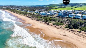 A coastal area with a beach, ocean waves, and a cluster of modern houses. - 7 Boomer Drive, Port Elliot (Port Elliot)