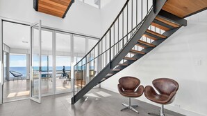 A modern interior with a spiral staircase, glass doors leading to a balcony, and two leather chairs. - 7 Boomer Drive, Port Elliot (Port Elliot)