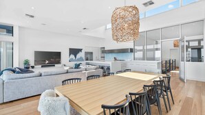 A modern living space with a dining area, kitchen, and a large window. - 7 Boomer Drive, Port Elliot (Port Elliot)