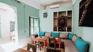 Un salon chaleureux avec une table en bois, un canapé agrémenté de coussins turquoise et un meuble décoratif.