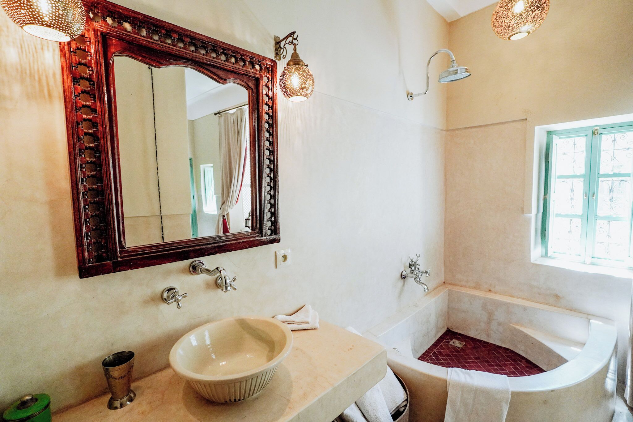 A bathroom with a large mirror, a sink, a bathtub, and a window.
