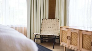 Una habitación con una cama, un sillón de mimbre y un armario de madera.
