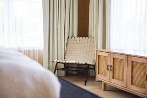 Una habitación con una cama, un sillón de mimbre y un armario de madera.