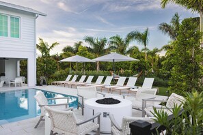 A pool area with lounge chairs and umbrellas, surrounded by lush greenery.