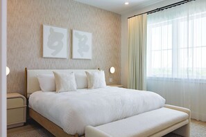 Ein modernes Schlafzimmer mit einem großen Bett, Nachttischen und einem Fenster mit Vorhängen.