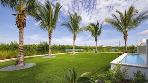 A well-maintained lawn with palm trees and a swimming pool. - The Fairhaven House at Solaire Lunara Bay (Key West)