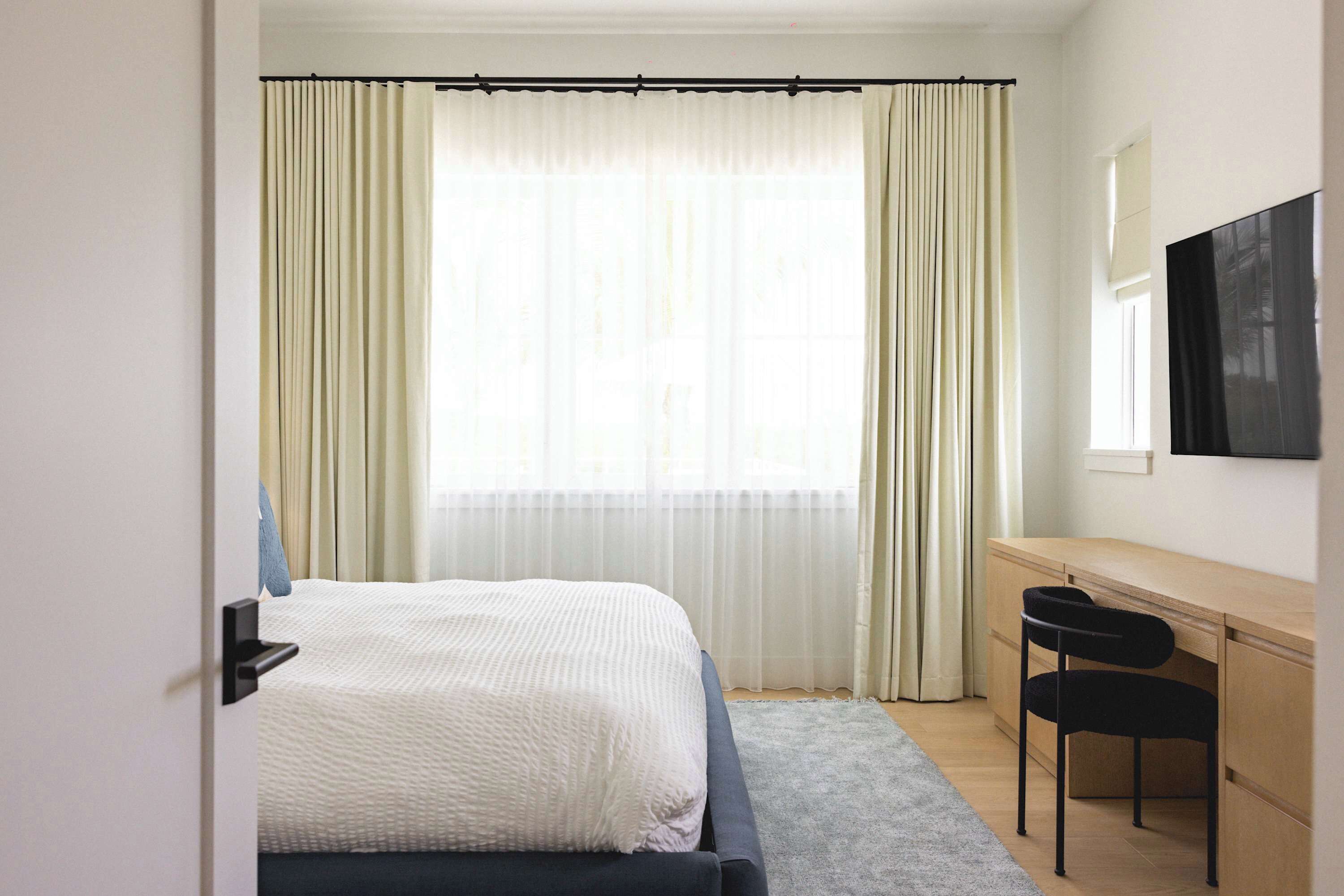 A bedroom with a bed, a desk, and a chair.