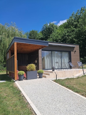 A modern house with a covered porch, a large sliding glass door, and outdoor seating.