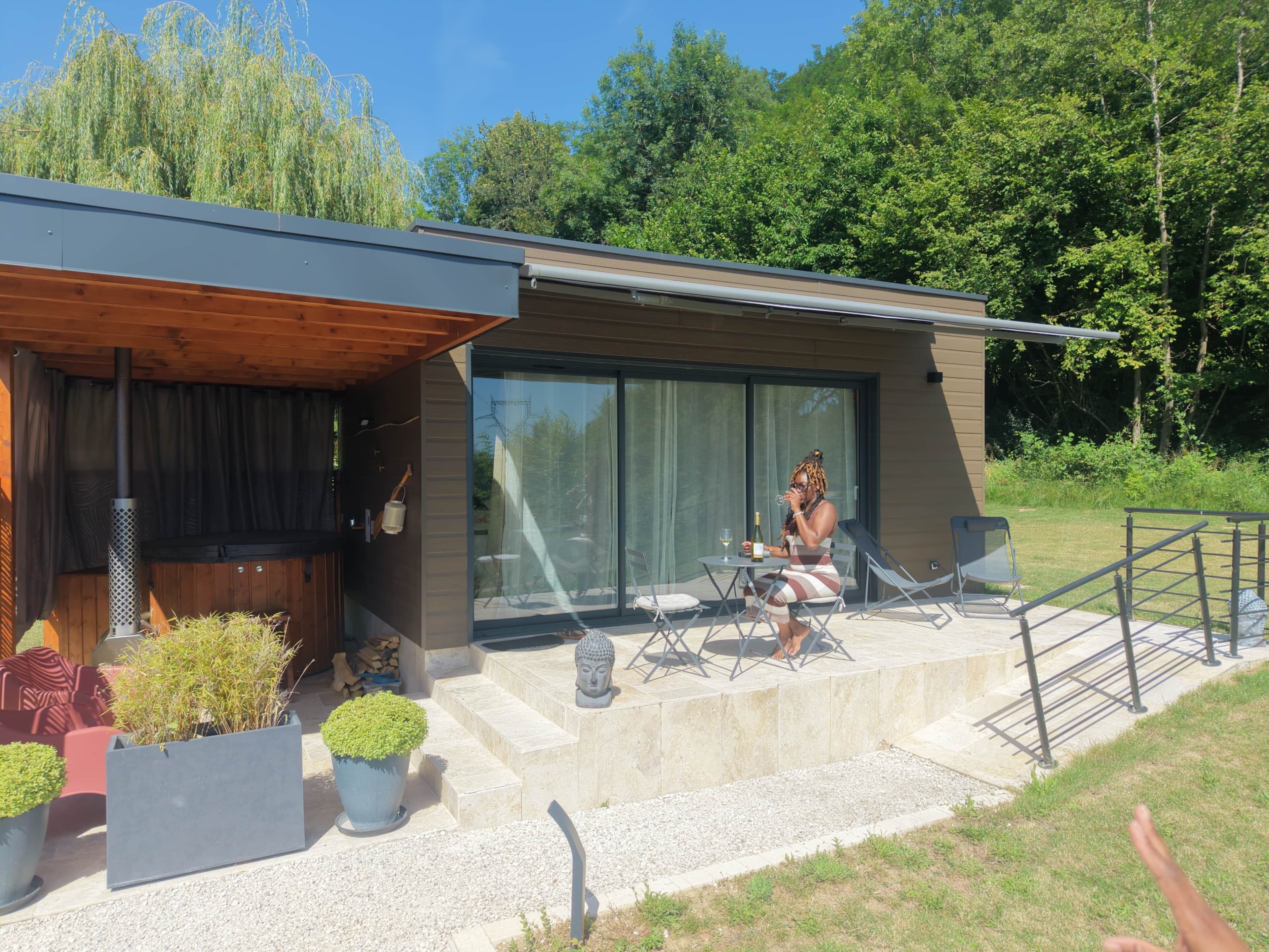Una casa moderna con un patio, mobiliario exterior y un amplio ventanal.