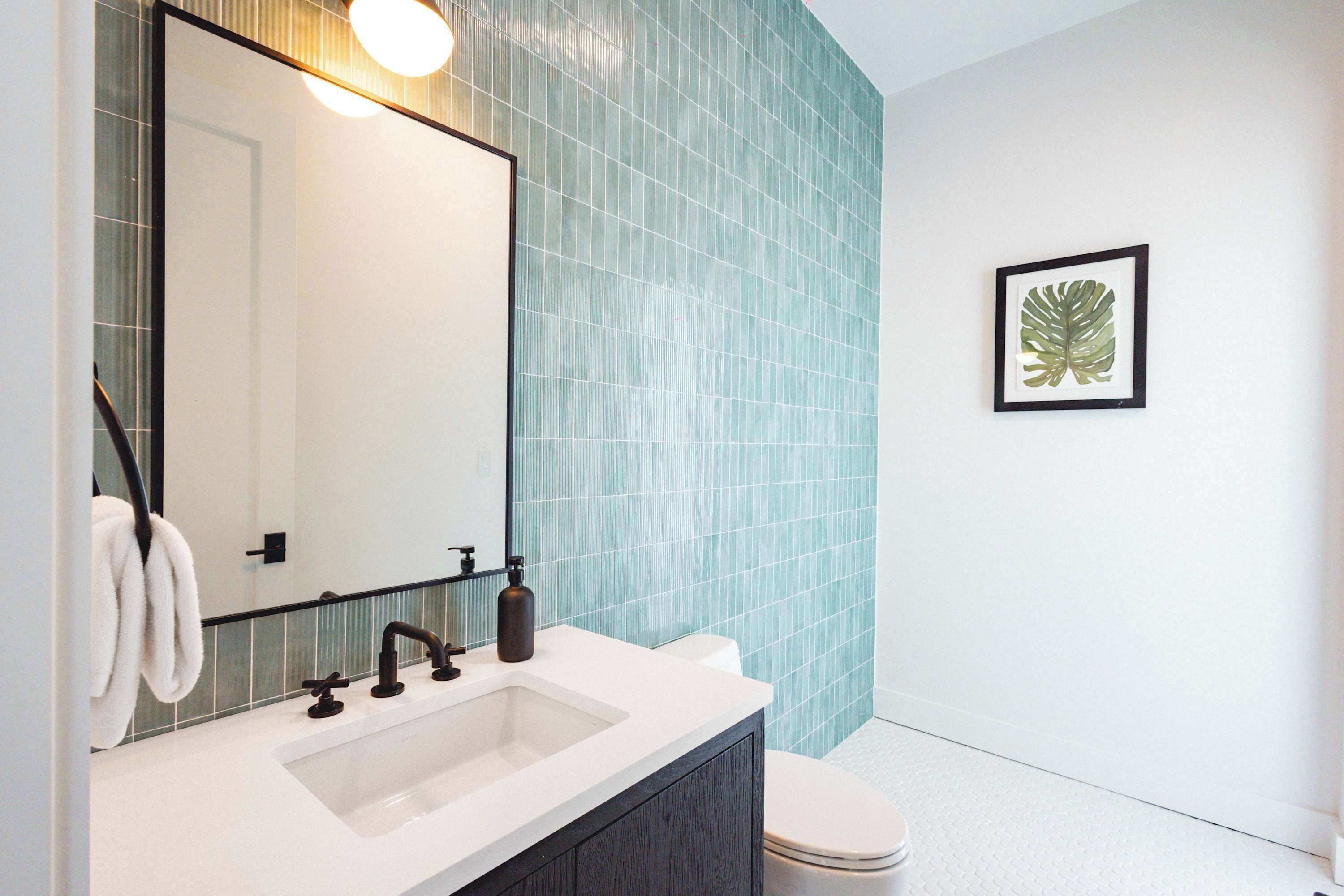 Une salle de bain avec un lavabo blanc, un meuble en bois foncé et des toilettes.