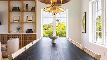 A modern dining room with a dark wooden table, a central bowl, and a bookshelf with books and decorative items.