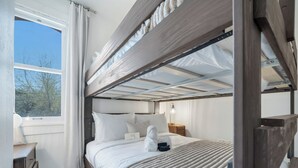 Ein Schlafraum mit Etagenbetten, einem Fenster, einem Nachttisch und einer Lampe.